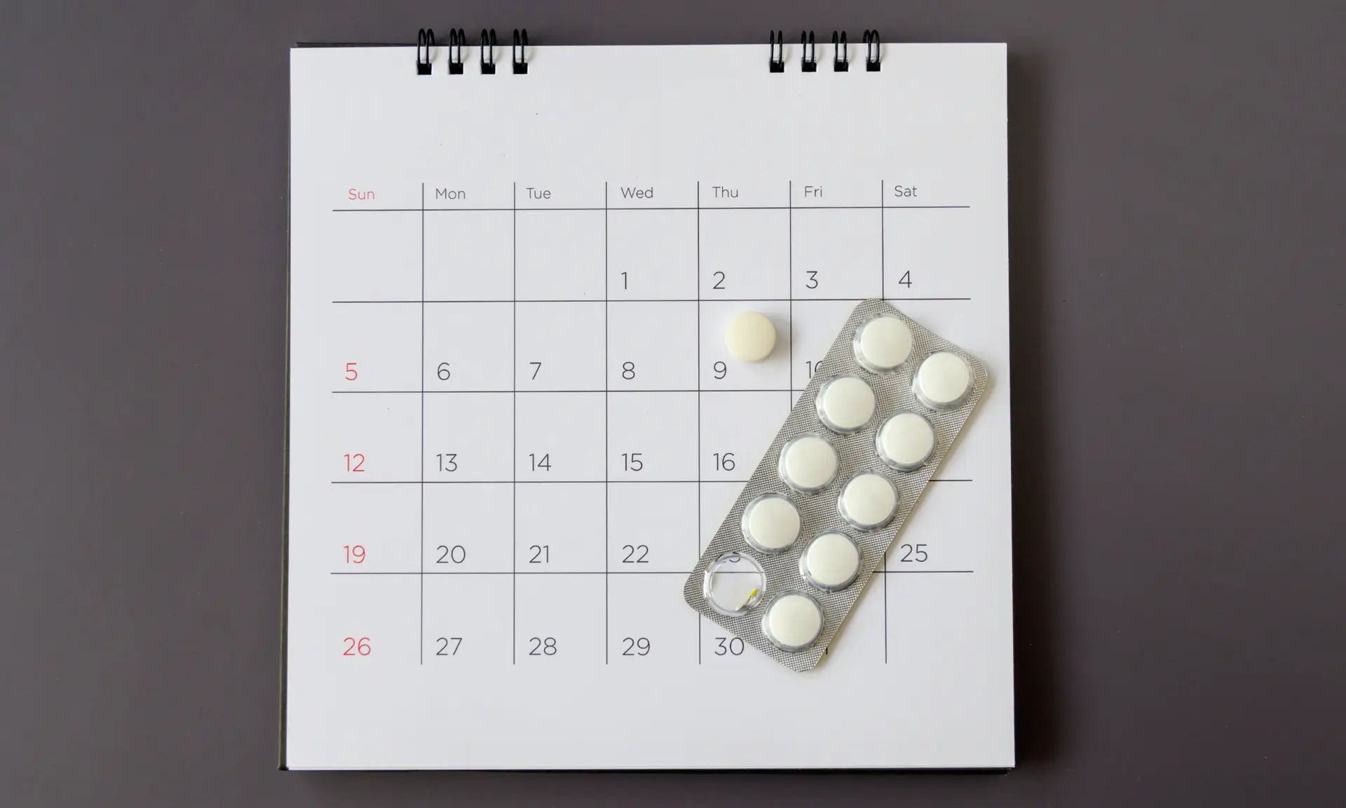 Calendar with pills representing a late period