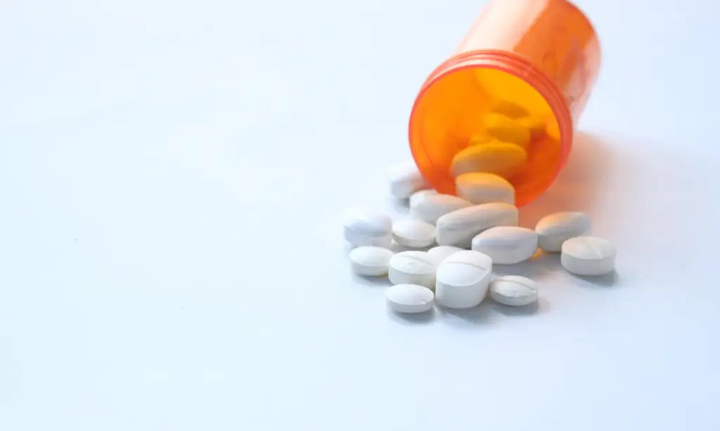 Frasco de pastillas con píldoras abortivas derramándose.